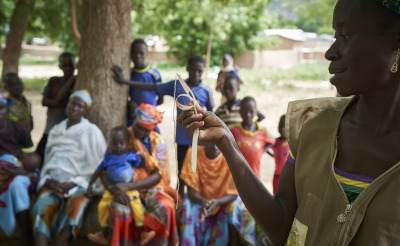 At a community training, a member of our team trains parents how to use a color-coded measuring band to check their children's nutrition status.