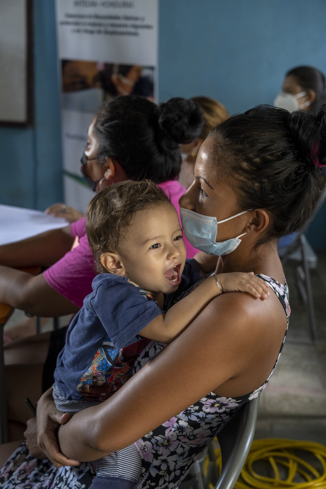 A mother sit and holds her child.