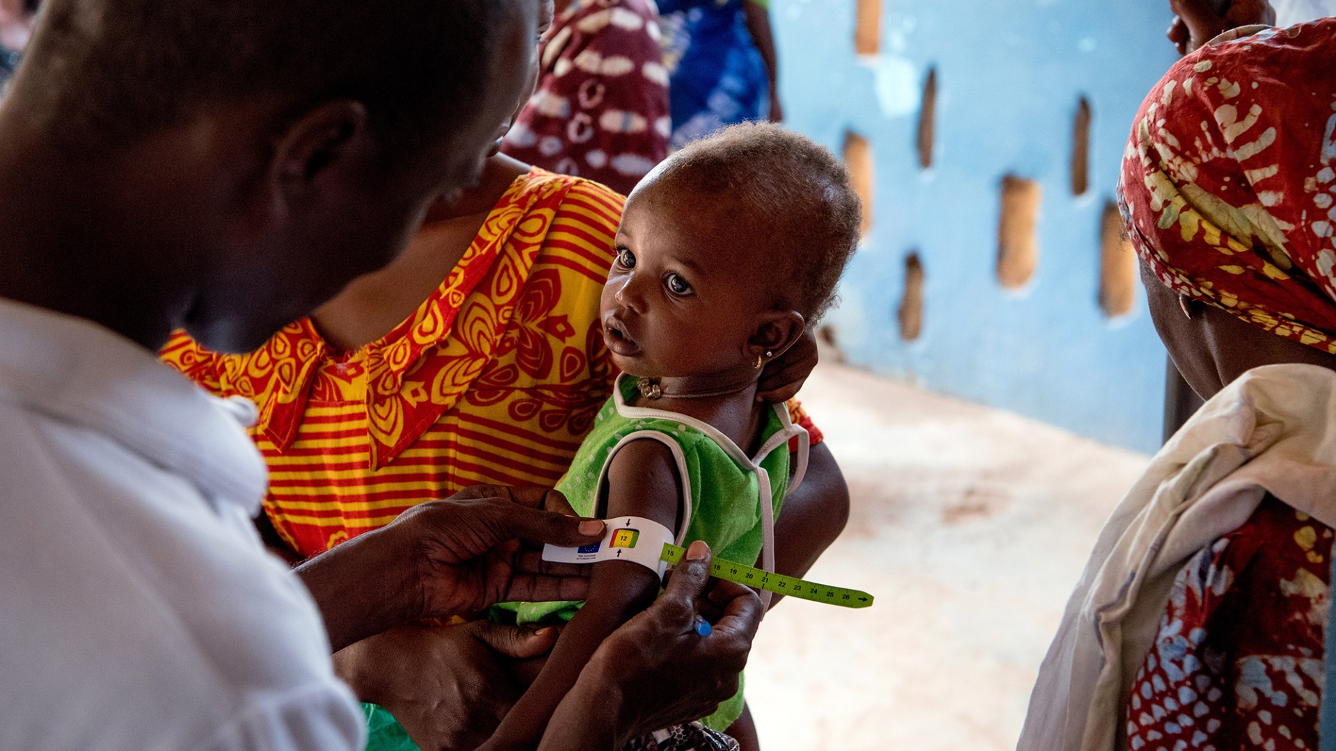 A child's arm is measured with a color-coded band to detect her nutrition status.