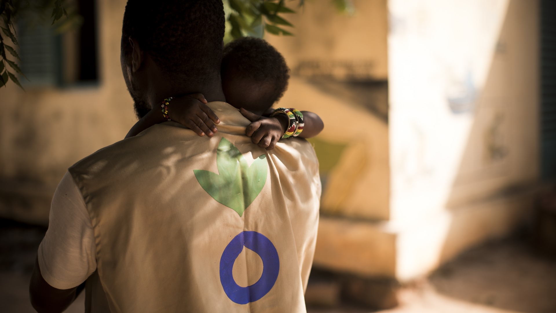 An Action Against Hunger Aid Worker holds a child in his arms in Mali.
