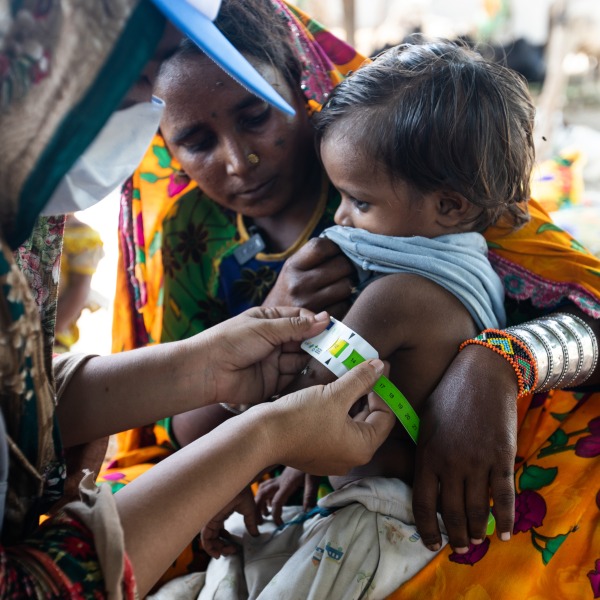 Samina (right), an Action Against Hunger Community Health Worker, checks 4-year-old Kailash's arm with a color-coded measuring tape to see if he has gained weight since her last visit.