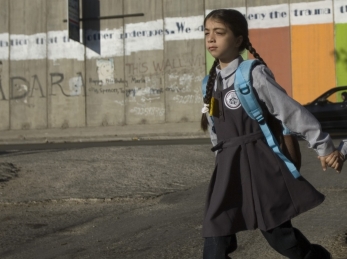 A girl and boy walk past the annexation and separation wall built by the Israeli government in the West Bank on their way to school © Courtesy of WeWorld to Action Against Hunger.