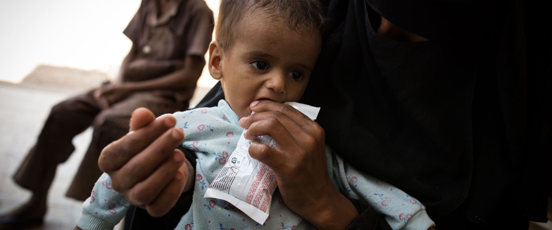 A child receives treatment for malnutrition from his mother