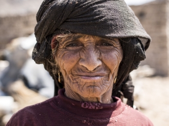 In Yemen, a woman stands in front of her community, which has been destroyed by conflict.