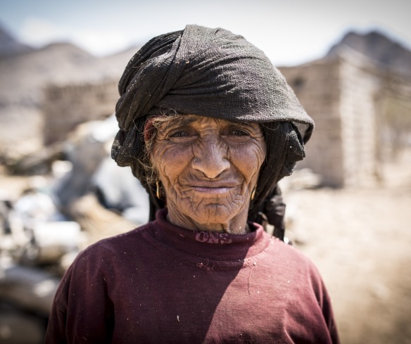 In Yemen, a woman stands in front of her community, which has been destroyed by conflict.